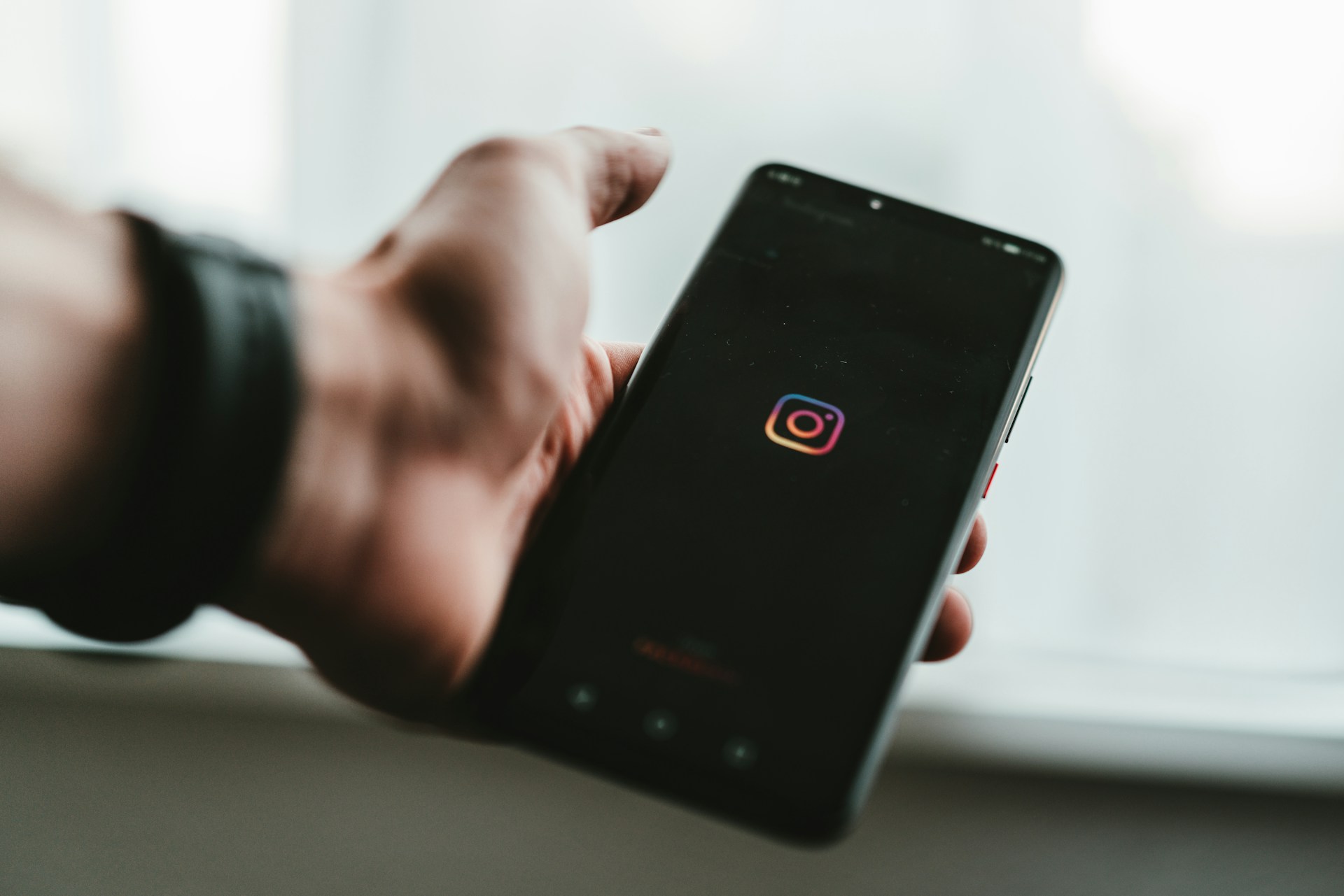 Ein Smartphone in der Hand ein Person. Auf dem Smartphone ist das Instagram Logo zu sehen.